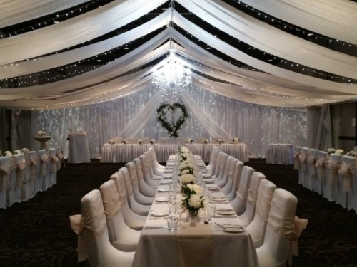 Champagne bows white long guest tables willow heart backdrop feature