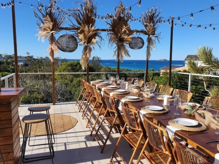 Festoon lighting dried botanical floral arrangements, bamboo chairs, timber topper tables