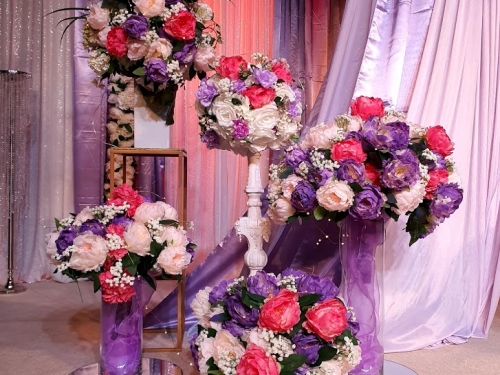 Stage decorations hot pink, pale pink. purple flowers in glass vases + pillars