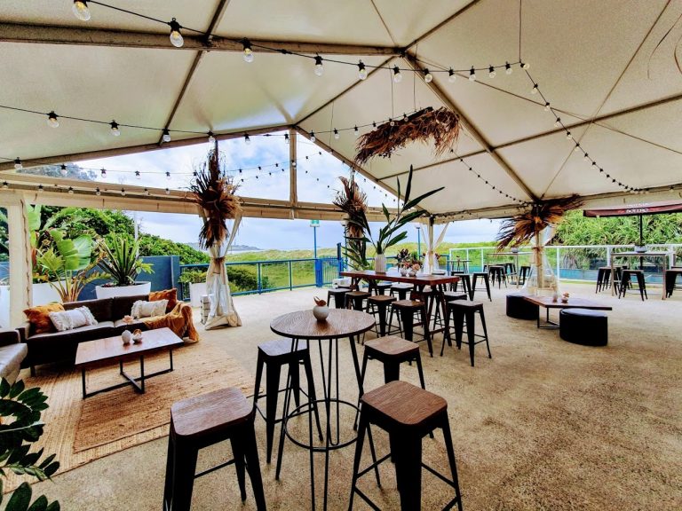 Marquee, festoon lighting, dried botanicals, white silk pole draping, timber saw table, timber coffee table black wrought iron, bamboo stools black base, bamboo high dry bars black base, jute rugs, fawn tasselled cushions, mustard cushions, mustard throw rug