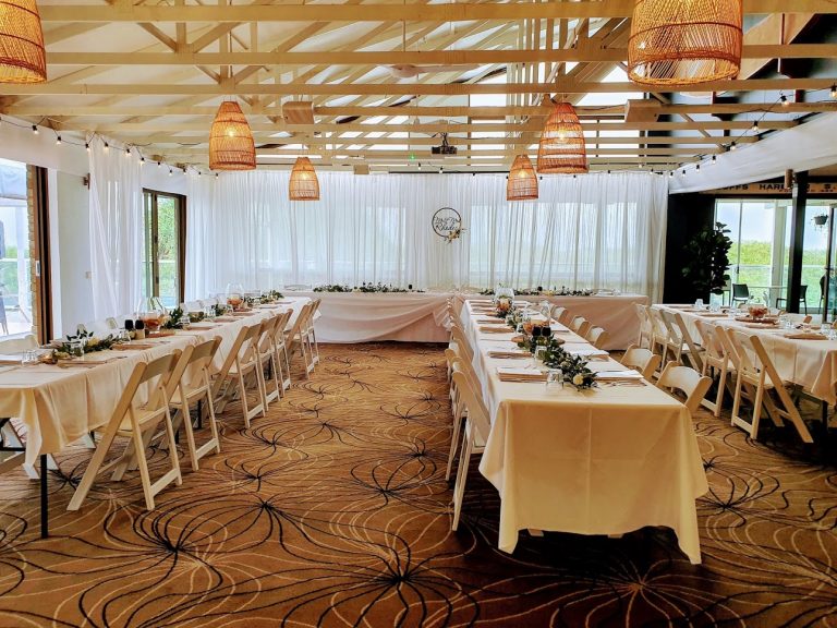 Festoon lighting, White satin backdrop on Eastern side, long white tables, Bridal skirt, White Malibus, Lotus glass vase  with remote candle, greenery